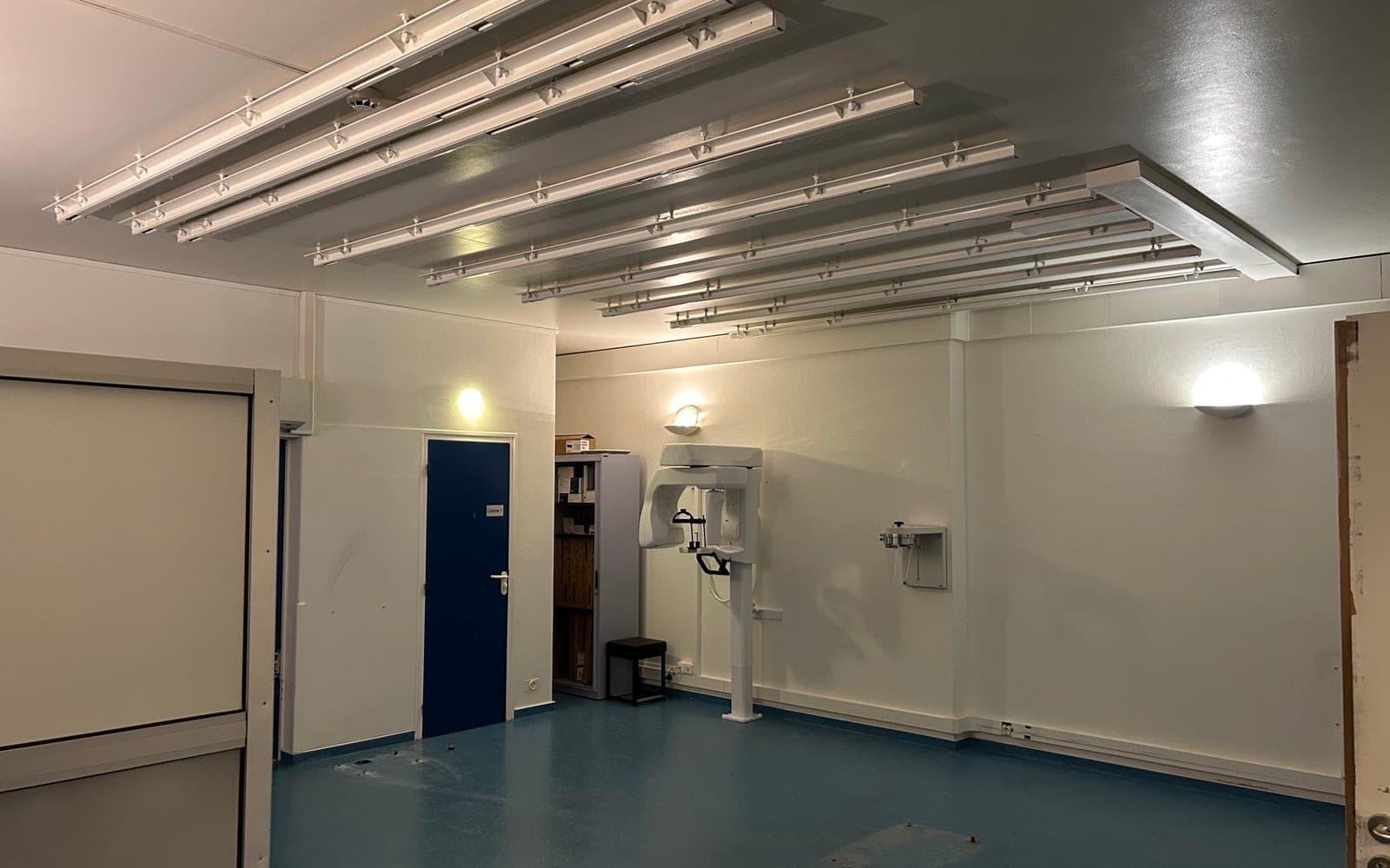 Salle de radiographie vidée après dépose, traces des fixations au mur et au plafond
